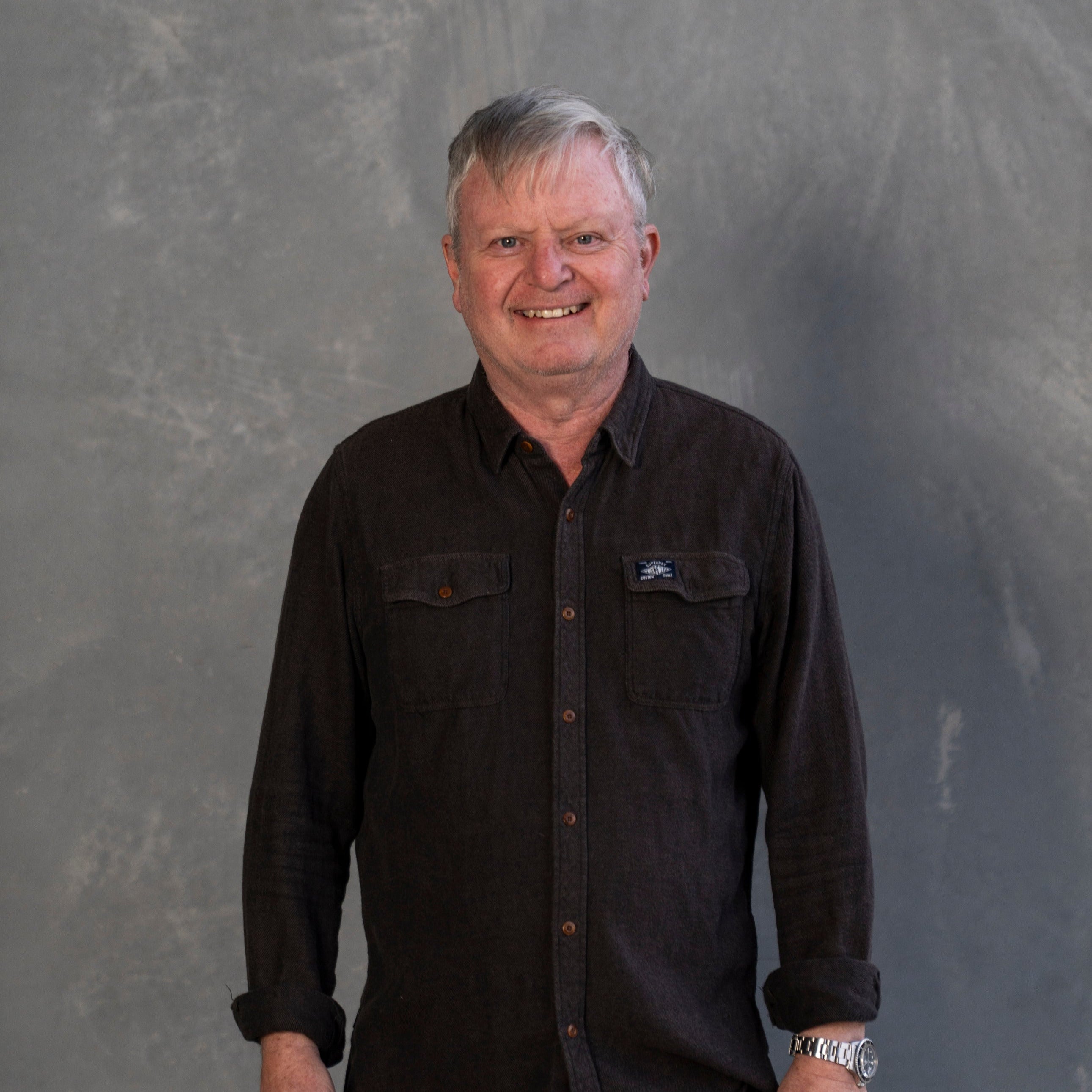 Man wearing a black shirt with a logo against a gray background