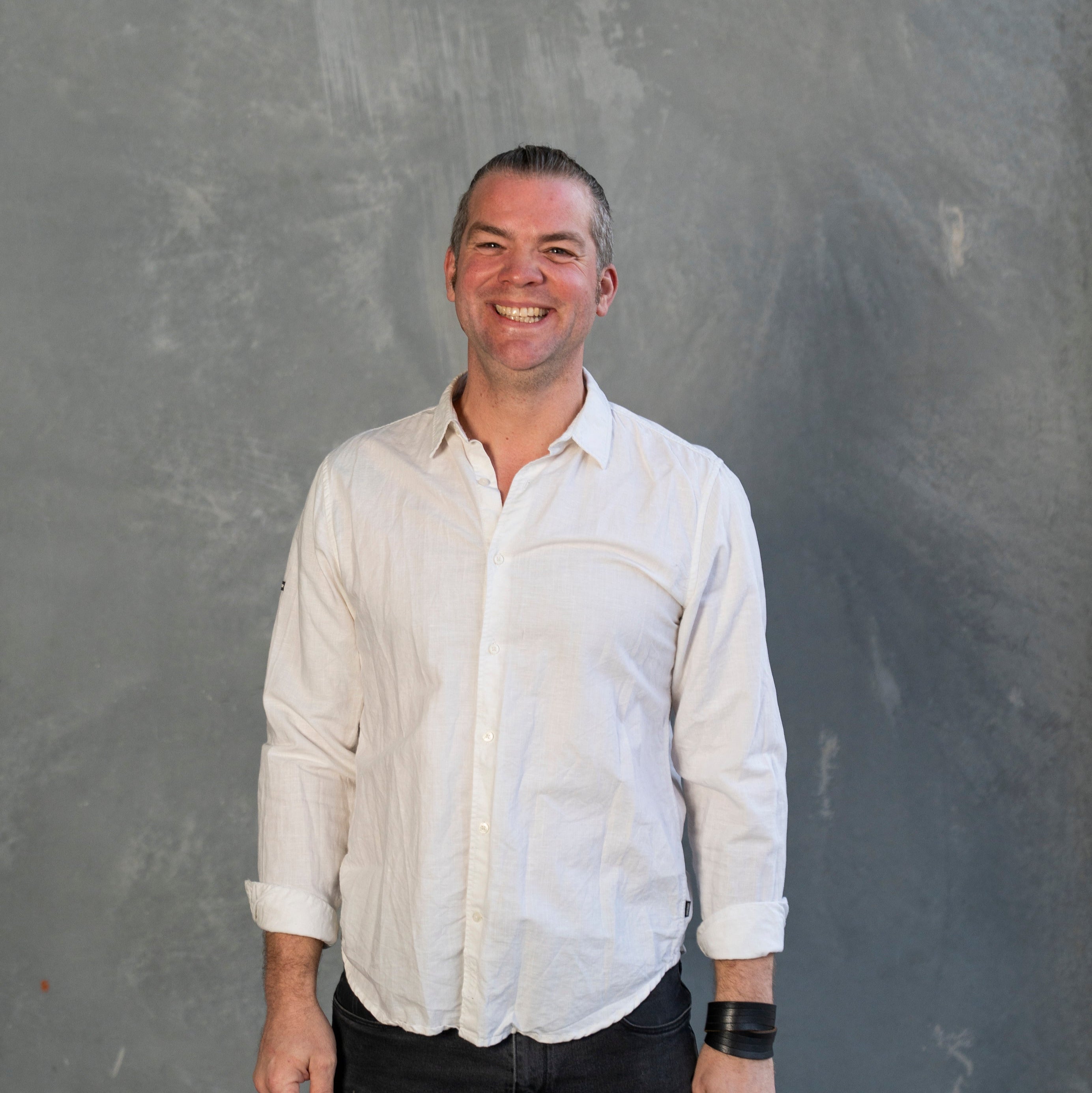 Man wearing a white shirt standing in front of a gray background